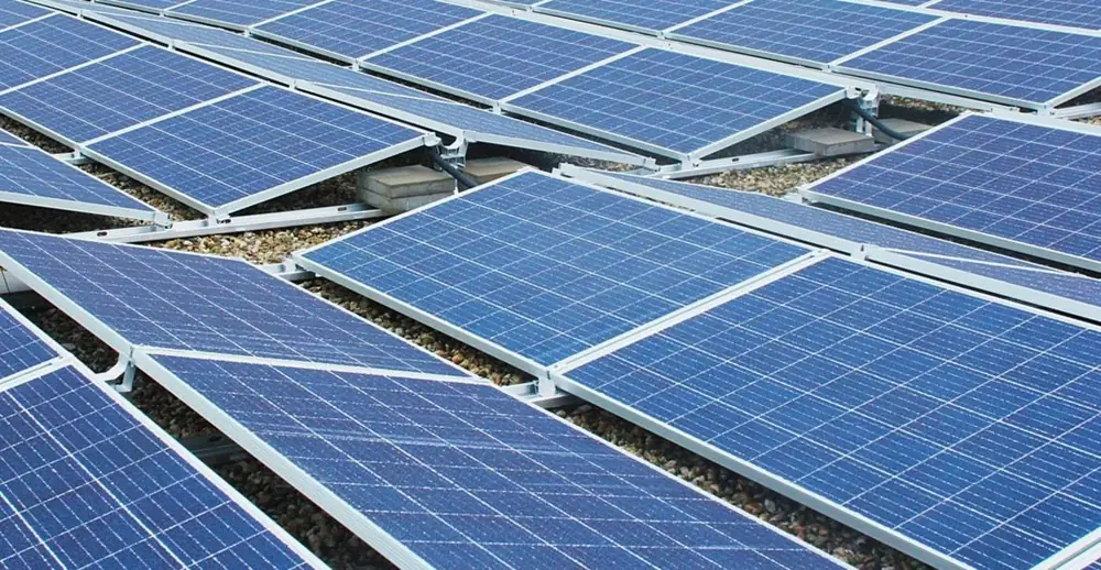 Rows of blue solar panels seen from a low angle on a flat roof (illustrative photo)